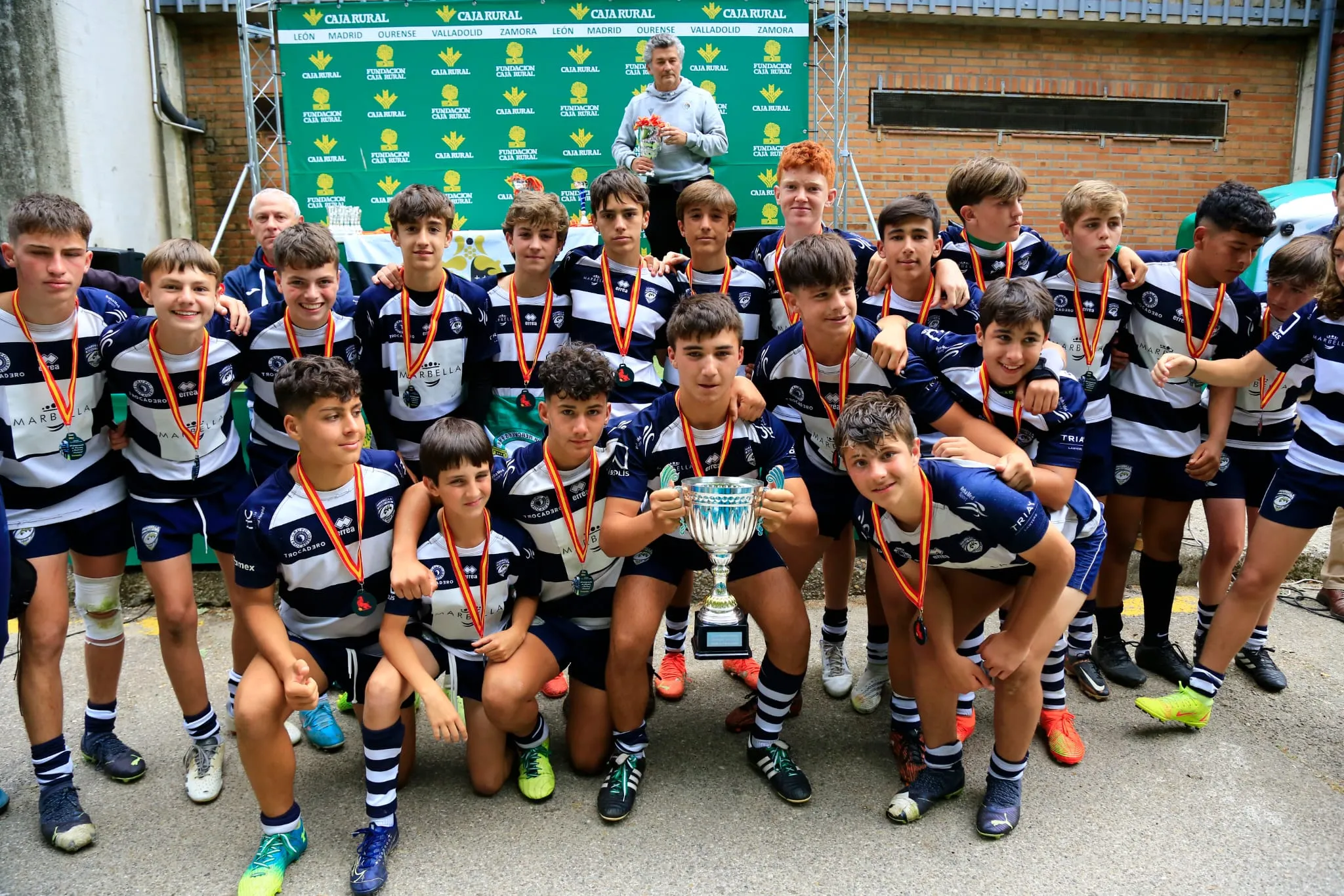 Equipo de rugby M14 celebrando un título con trofeo y medallas tras un campeonato nacional
